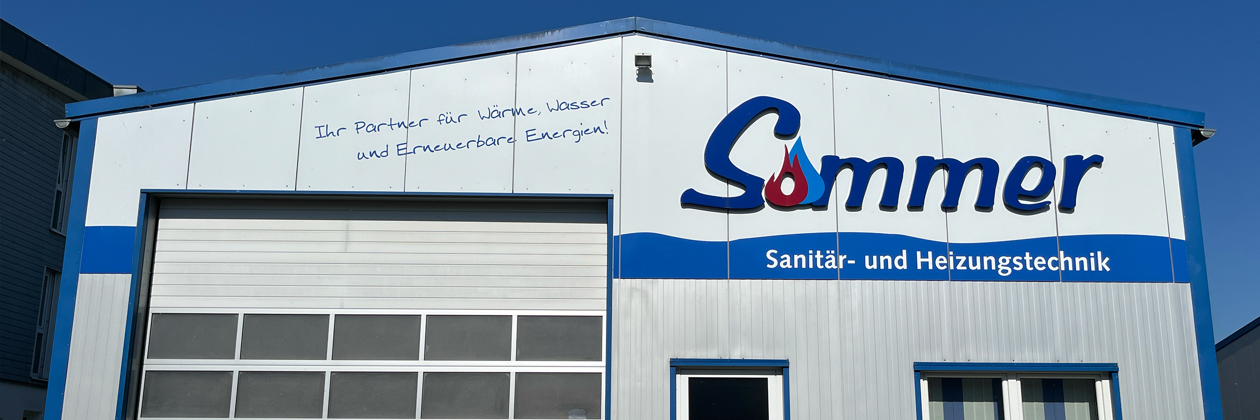 Firmengebäude der Sommer Sanitär- und Heizungstechnik mit Schriftzug „Ihr Partner für Wärme, Wasser und Erneuerbare Energien.